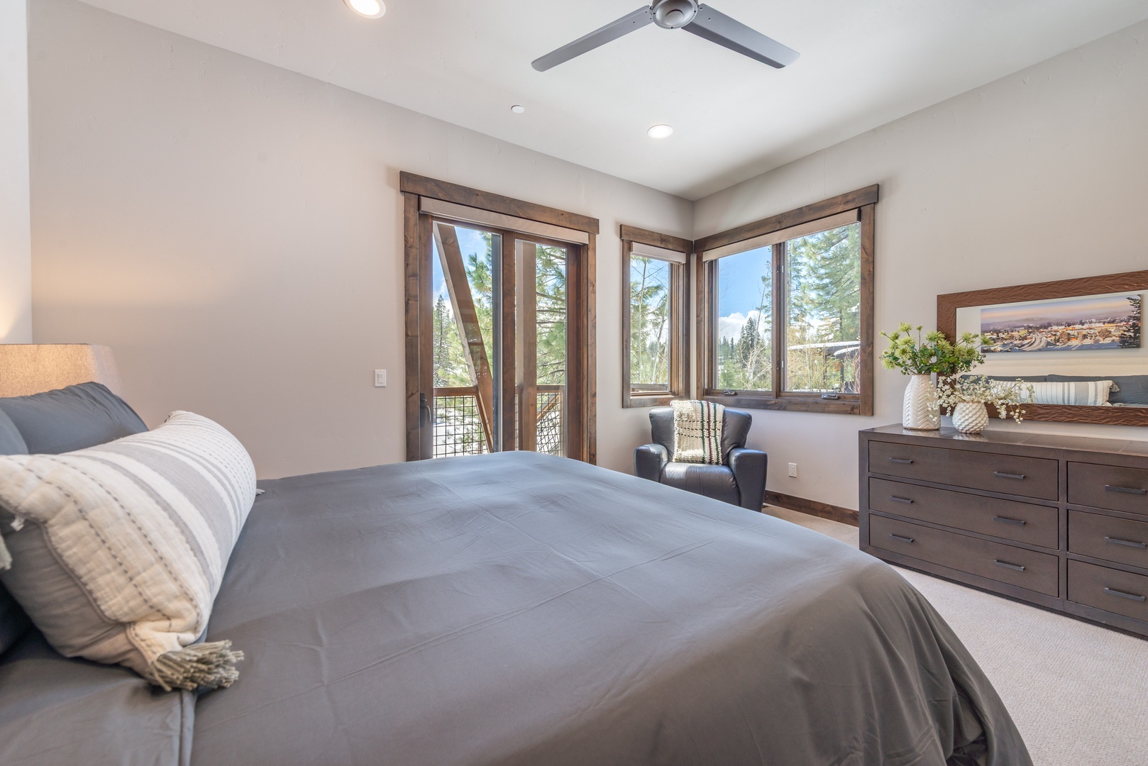 Unwind in your serene bedroom where warm wood accents meet mountain views through expansive windows, creating your perfect retreat.