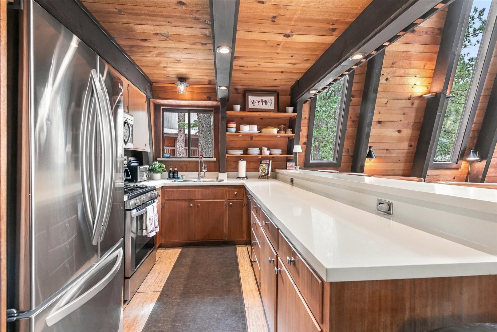 Cook your favorite meals in this modern mountain kitchen with stainless appliances, ample counter space, and beautiful forest views through expansive windows.
