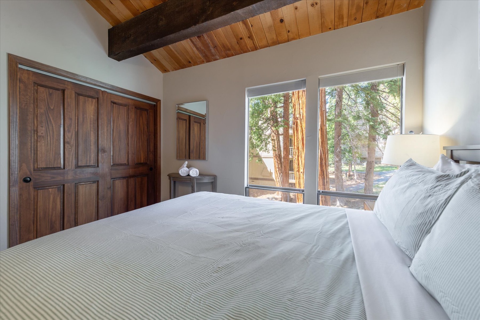 Sink into plush bedding while forest views greet you each morning through expansive windows in this rustic-chic retreat.