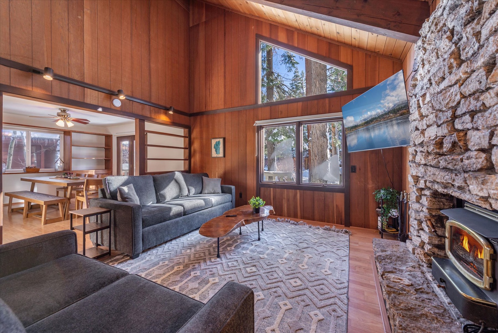 Cozy up in your warm living space with crackling fireplace, comfortable seating, and stunning natural views through floor-to-ceiling windows.