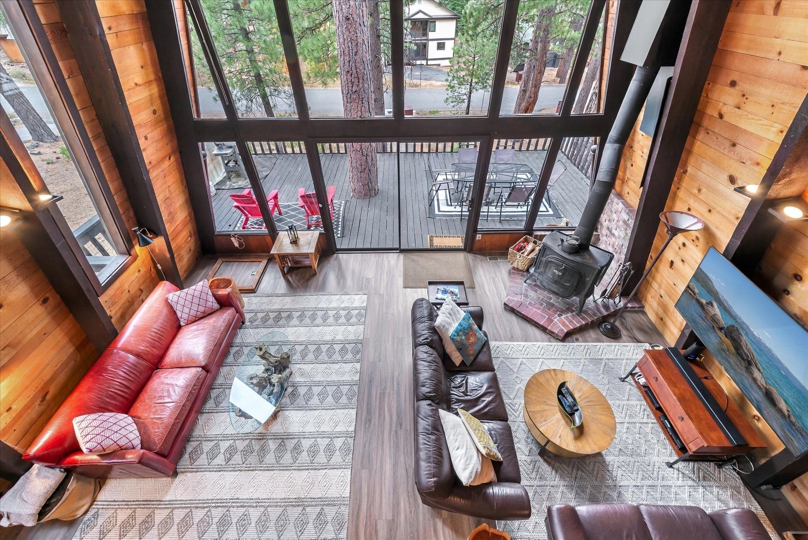 Settle into your cozy living space with soaring windows that frame the trees and deck beyond. Warm wood, plush leather seating, and a classic wood stove create the perfect mountain retreat atmosphere.