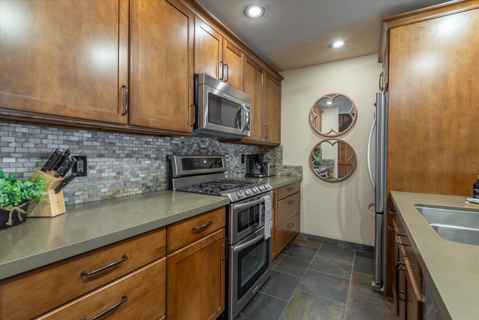 Your gourmet kitchen awaits with warm wood cabinets, gleaming appliances, and stunning tile backsplash perfect for cooking memorable meals.
