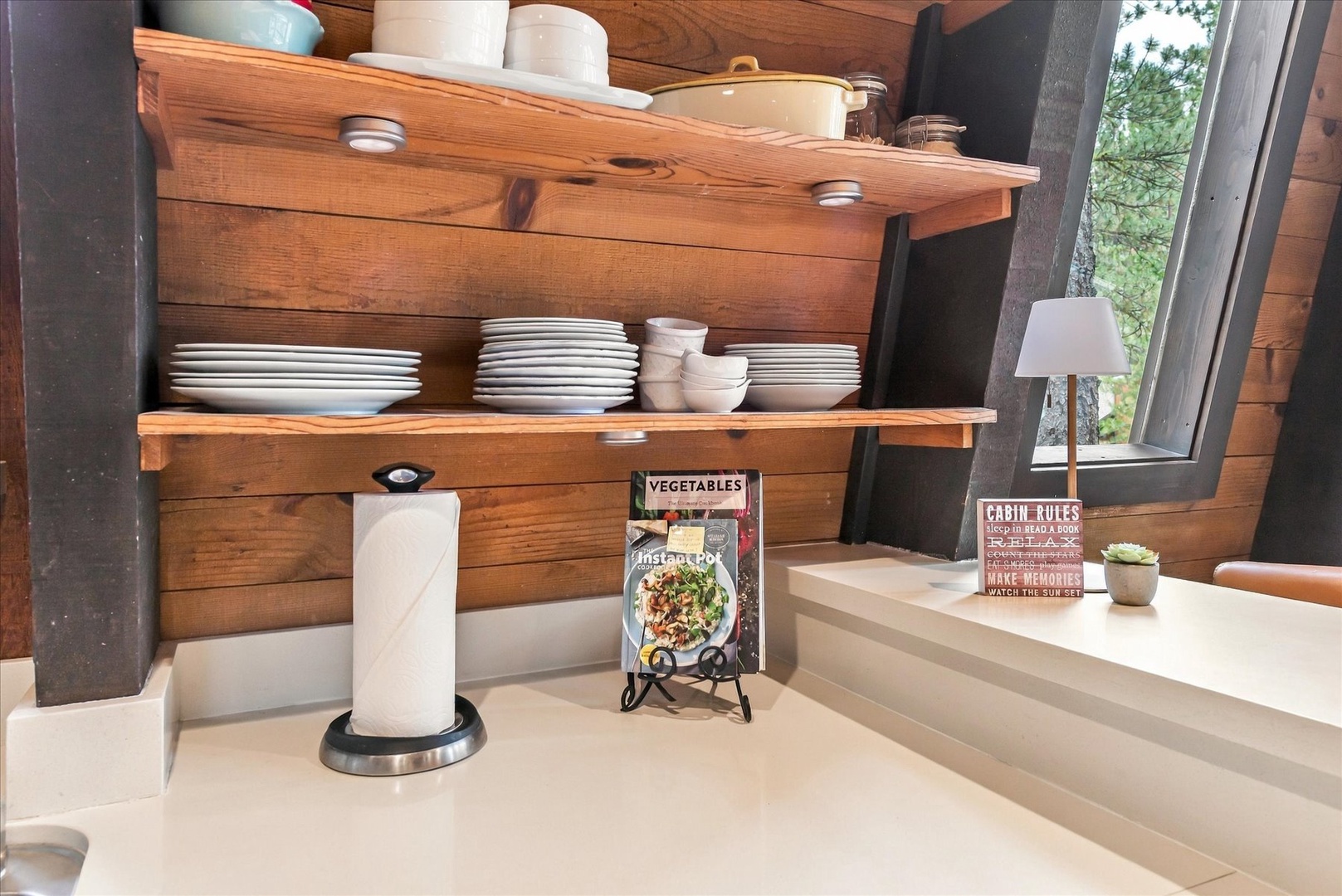Your cozy cabin kitchen features rustic wooden shelving stocked with everything you need, warm natural light, and charming details that make this space feel like home.