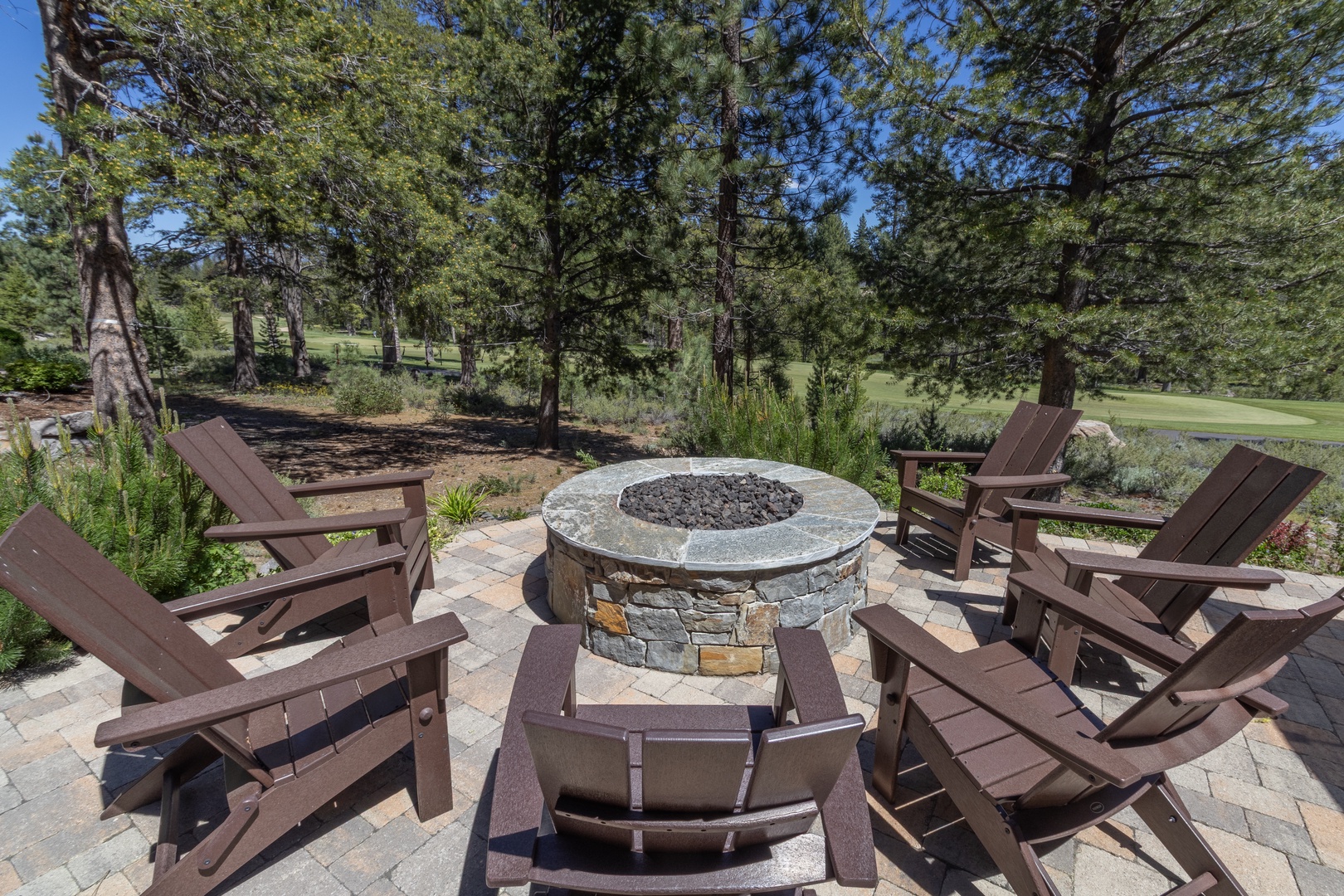 Gather around the stone fire pit surrounded by Adirondack chairs, where you can unwind beneath towering pines and enjoy views of the adjacent golf course fairway.