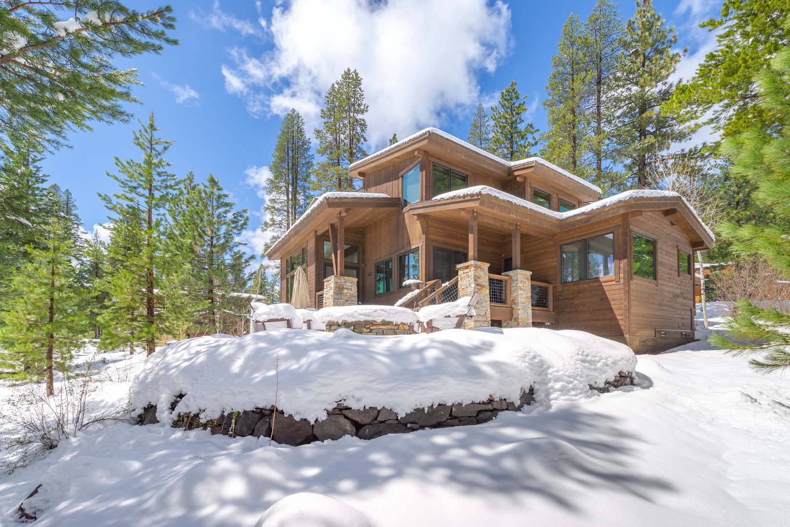 A stunning mountain lodge nestled among snow-dusted pines, featuring warm wood architecture and stone accents in a pristine winter setting.