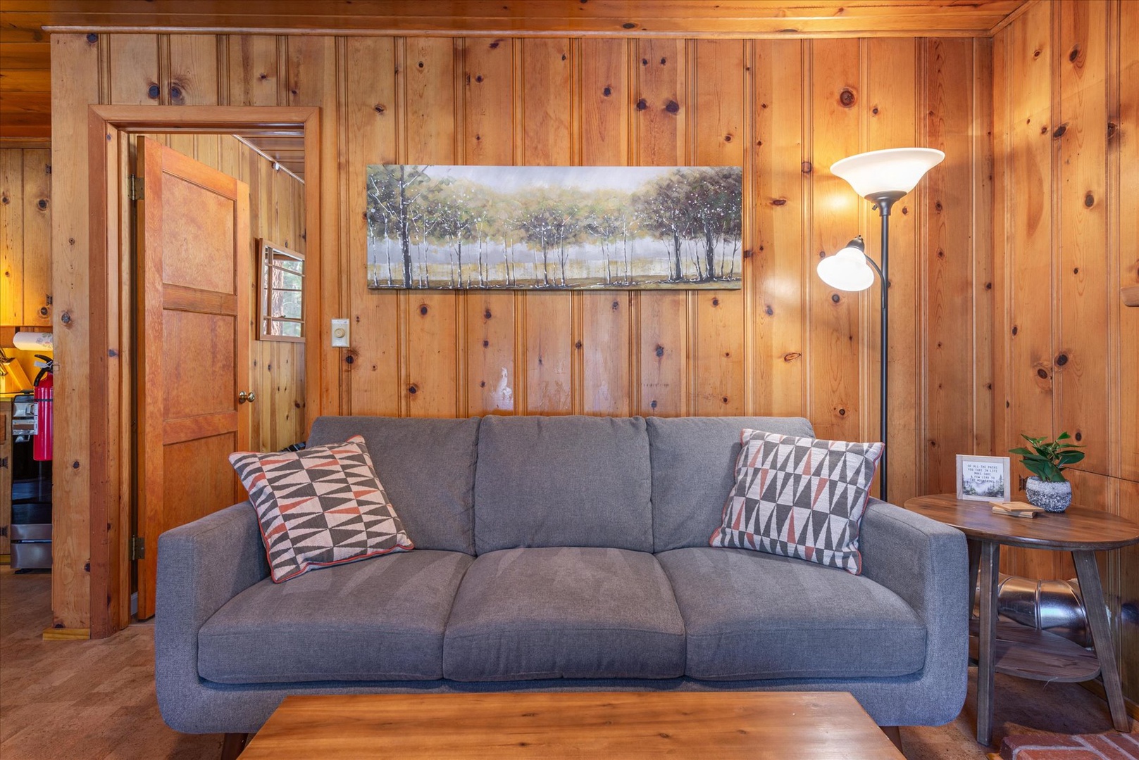 Relax on your plush sofa surrounded by warm wood paneling that creates the perfect cozy cabin atmosphere for your getaway.