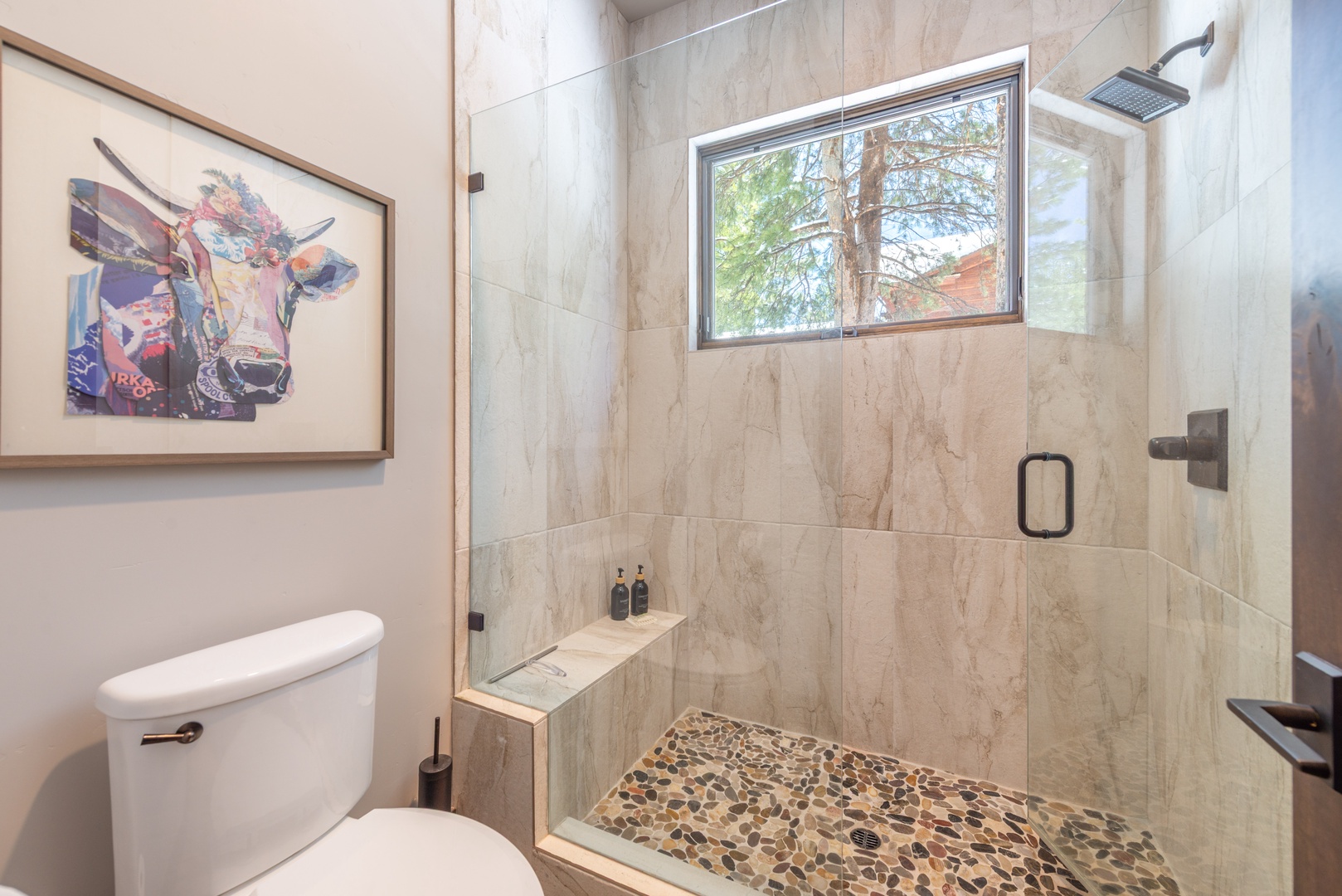 Step into your spa-like bathroom where marble surrounds meet a luxurious glass-enclosed shower with rainfall head and natural stone floor.