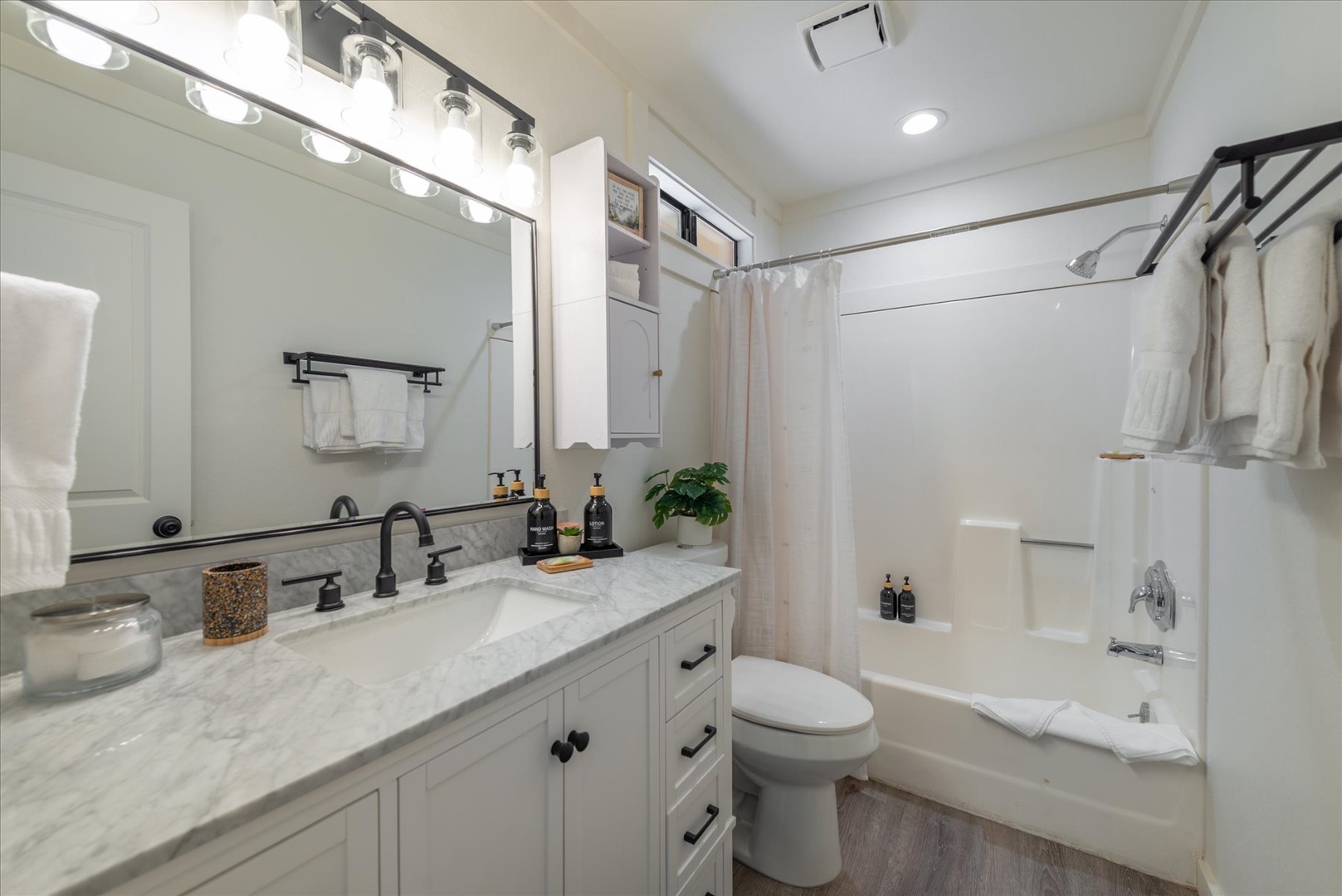 Step into your spotless bathroom featuring elegant marble counters, modern fixtures, and plush towels waiting for you. Enjoy the sleek tub-shower combo and bright vanity lighting for your daily refresh.