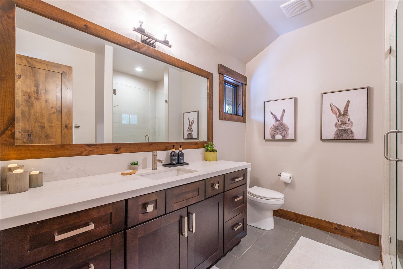 Refresh in your beautifully appointed bathroom featuring rustic wood accents, elegant vanity, and charming bunny artwork that brings warmth to your daily routine.