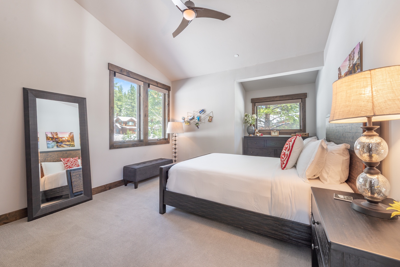 Unwind in your serene bedroom with crisp linens, elegant decor, and forest views through large windows.