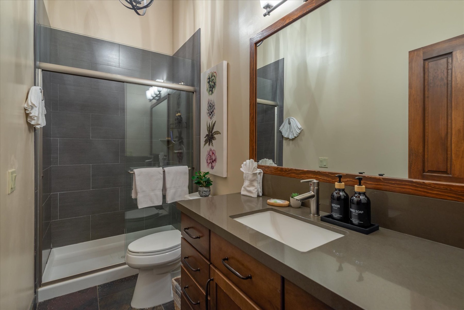 Step into your second floor bathroom featuring elegant gray tile, premium amenities, and fluffy towels ready for your arrival.
