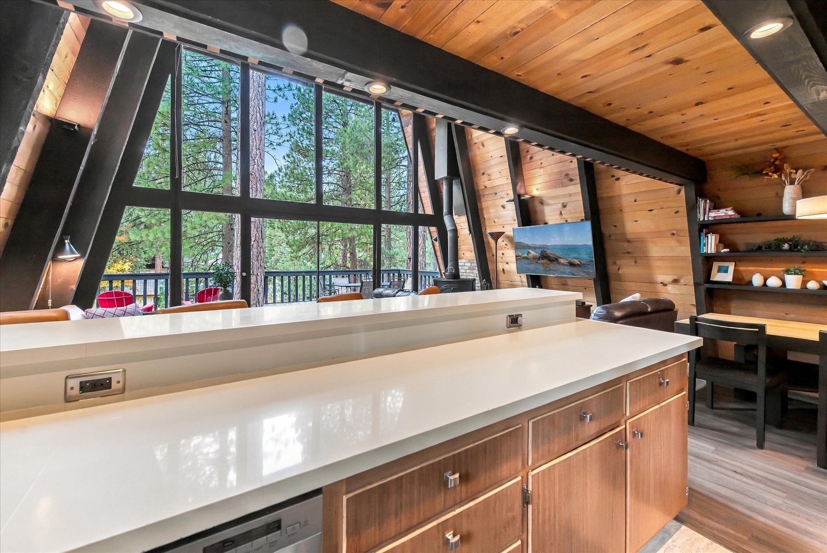 Sunlight pours through floor-to-ceiling windows framing towering pines, while sleek counters and warm wood create your perfect retreat for cooking and gathering.