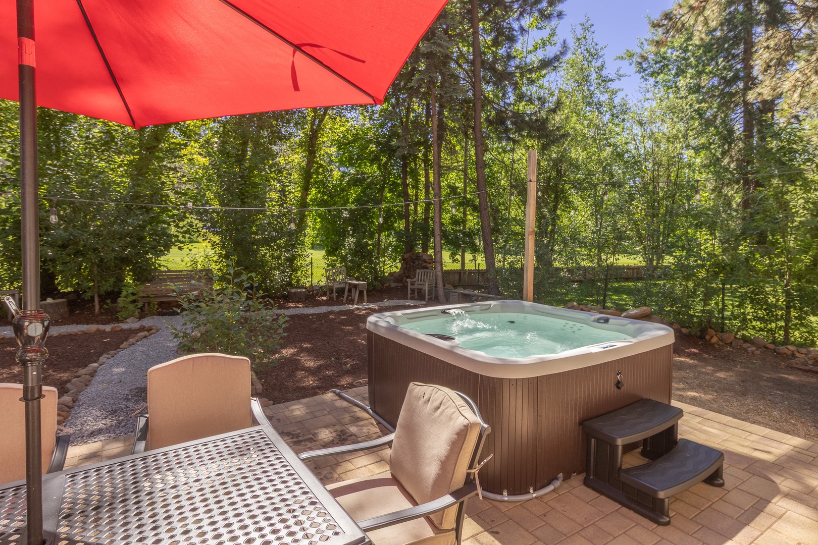 Unwind in your private hot tub surrounded by tranquil forest views, with comfy loungers and a shaded patio nearby—perfect for soaking, sipping, and savoring peaceful moments outdoors.