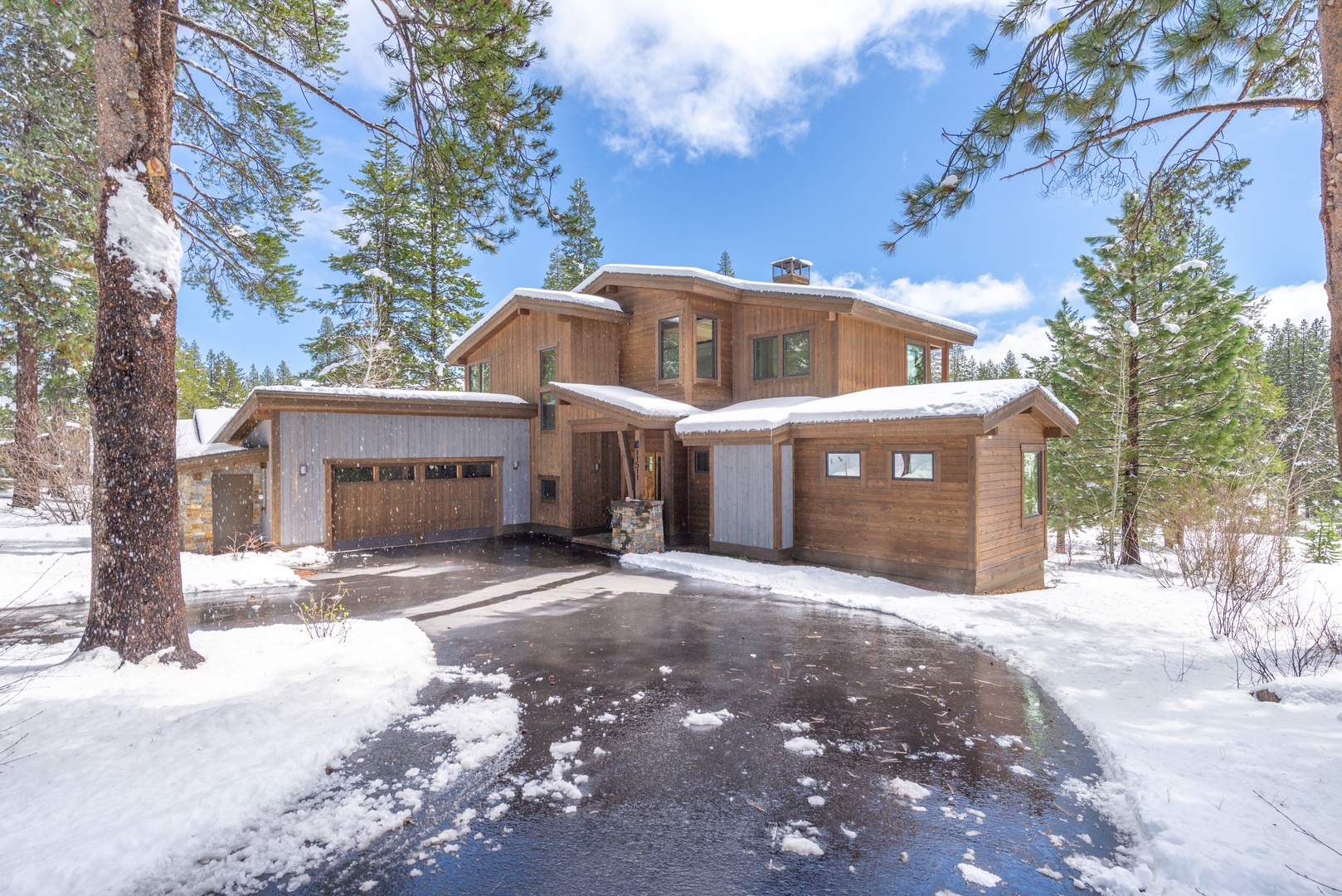 Modern mountain retreat nestled among snow-dusted pines with convenient garage parking for winter adventures.