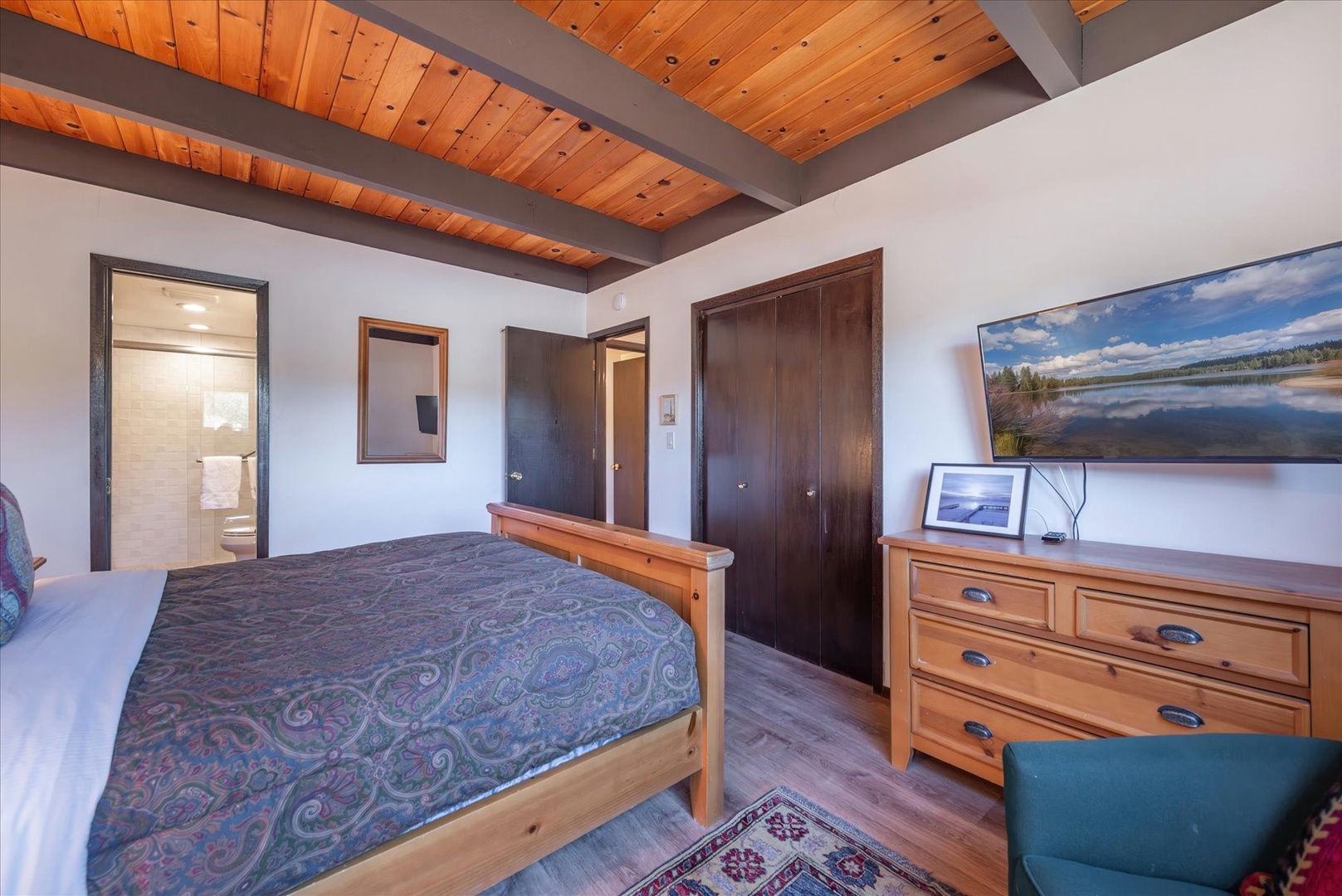 Relax in your rustic-chic bedroom featuring stunning wood-beam ceilings and peaceful lake views to help you unwind.