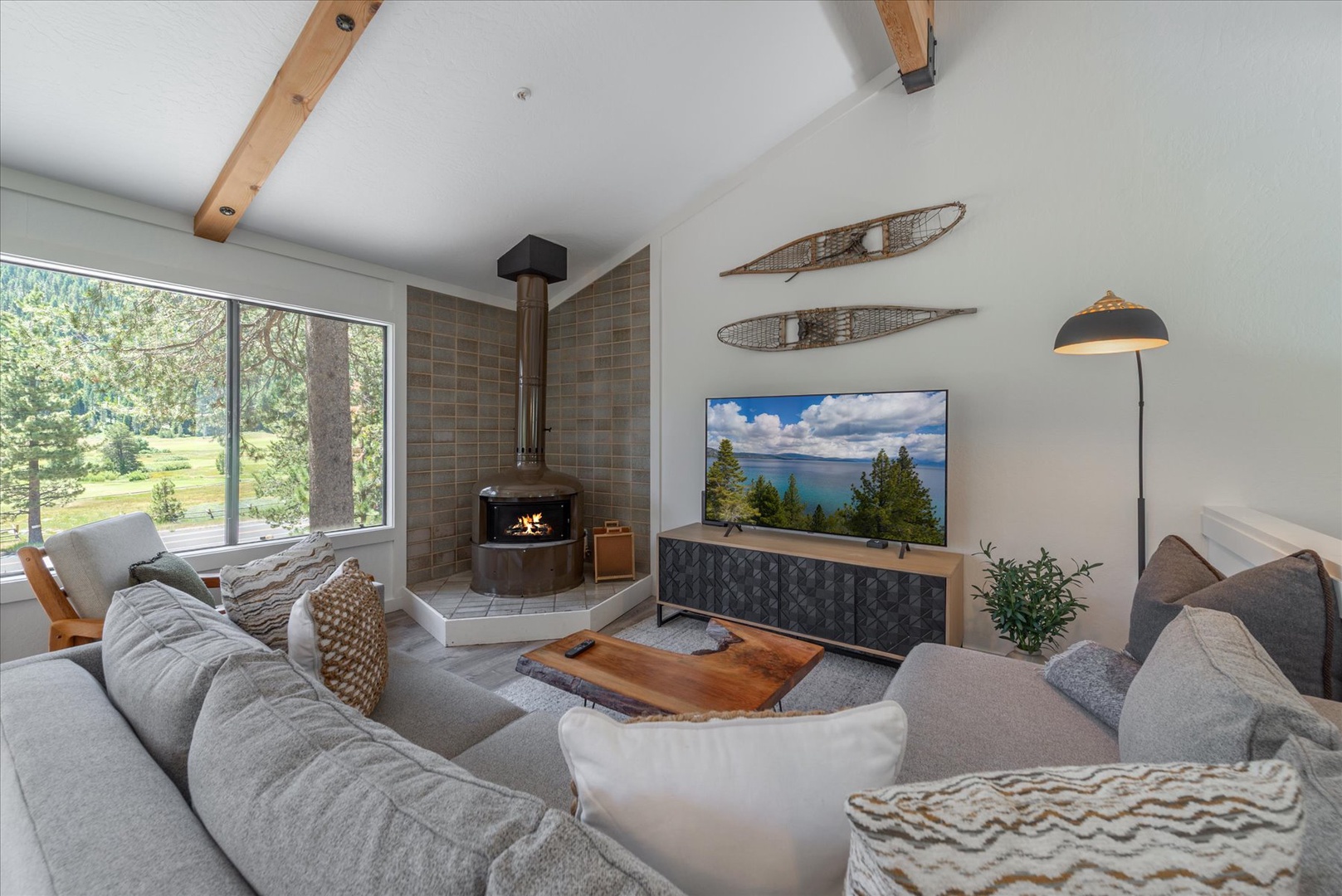 Unwind in your cozy living room with vaulted ceilings, exposed beams, and a crackling fireplace that sets the perfect mountain retreat ambiance. Sink into plush sofas and enjoy breathtaking forest views through expansive windows.
