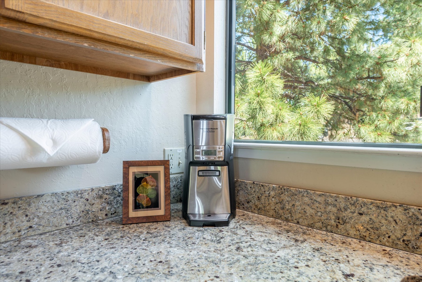 Your mornings start with fresh coffee from the in-house coffee maker, granite countertops, and serene pine tree views framing your kitchen window.