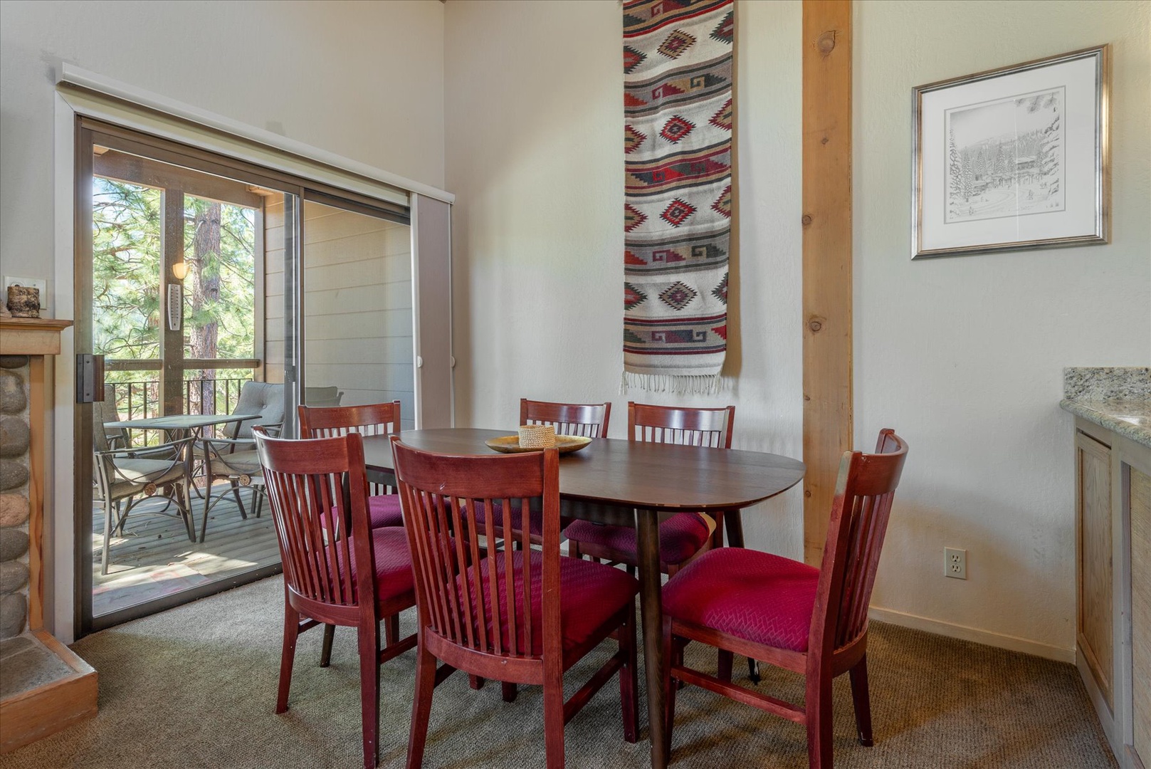 Gather around the inviting dining table where warm wood tones and colorful cushions set the stage for memorable meals together, while natural light streams through doors opening to your private outdoor retreat.