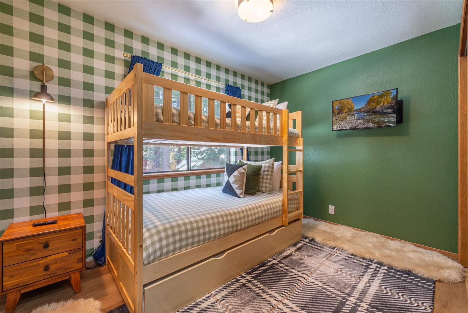 The bunk room features sturdy bunk beds and trundle with cheerful green plaid bedding, perfect for families or friends sharing adventures together.