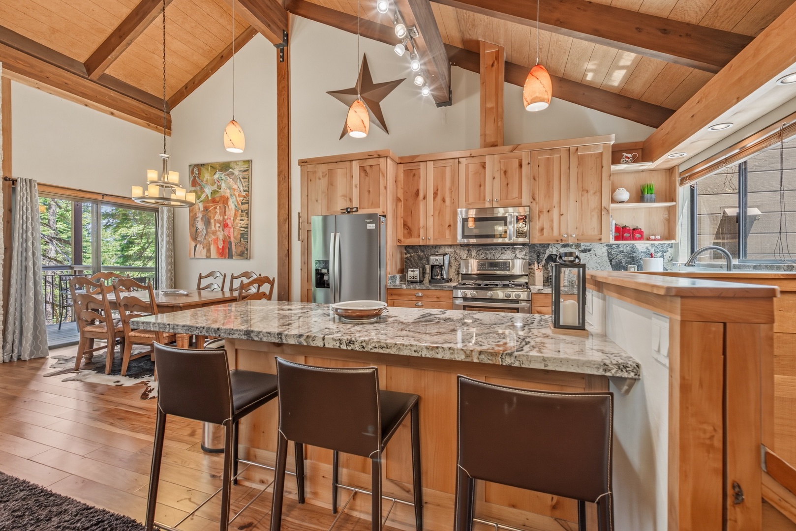 Step into your open-plan kitchen and dining area where warm wood tones and soaring vaulted ceilings create an inviting mountain retreat. Gather around the spacious granite island or enjoy meals with forest views.