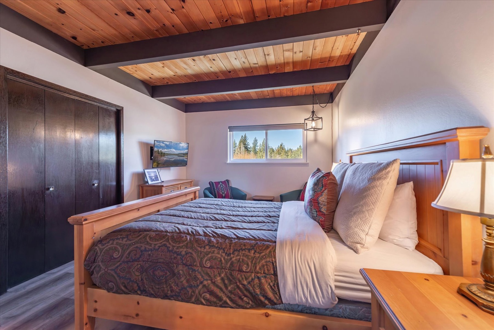 Rest beneath rustic wood beams in your cozy bedroom, where morning light streams through windows revealing forest views.