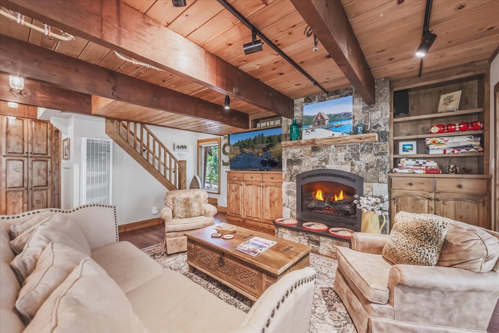 Unwind in your cozy living room with vaulted wood ceilings, plush seating, and a crackling stone fireplace that sets the scene for peaceful mountain evenings.