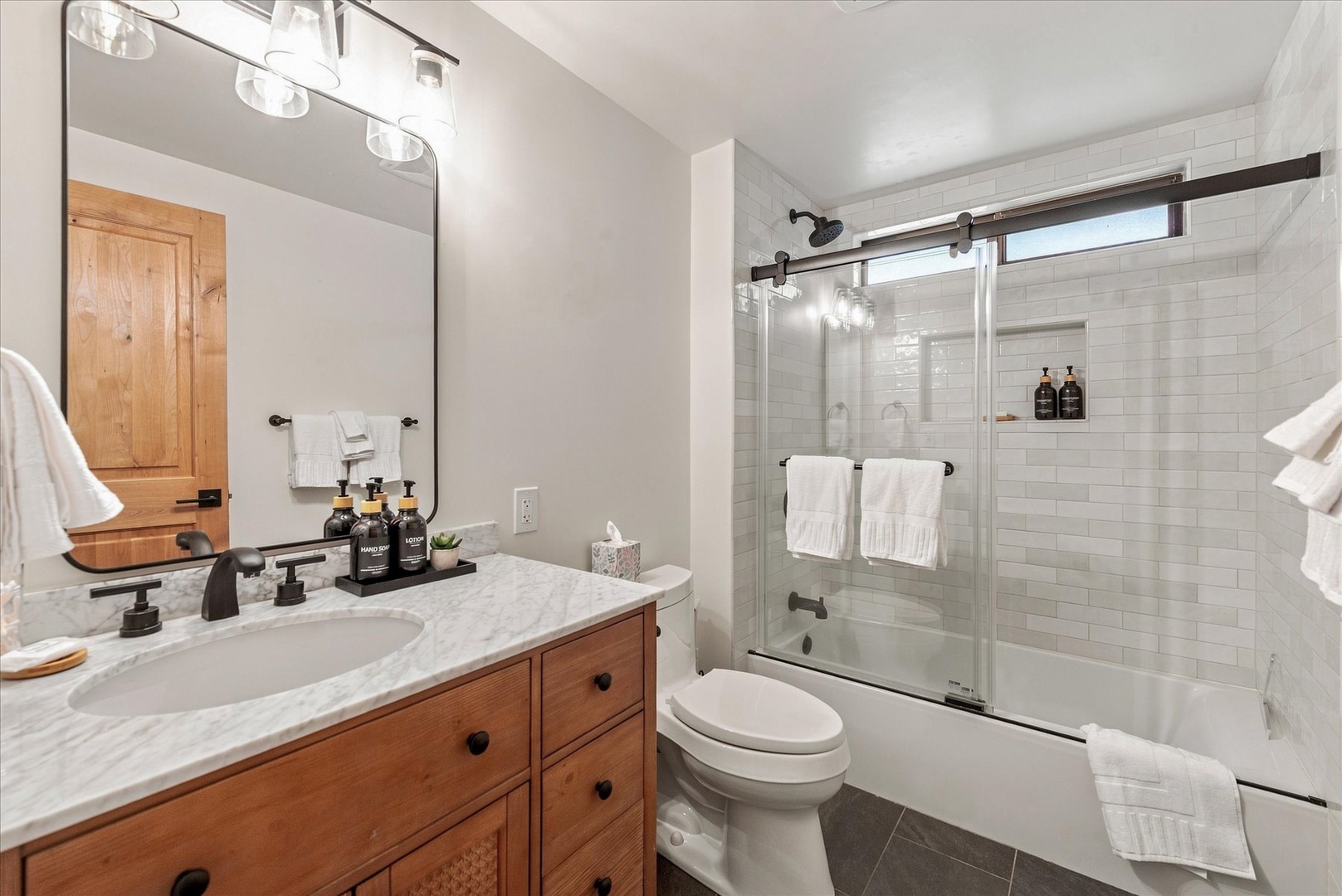 Step into your beautifully appointed bathroom, where soft lighting, marble countertops, and a sleek glass-enclosed tub await. Fresh towels and upscale bath amenities ensure you feel pampered from the moment you arrive.
