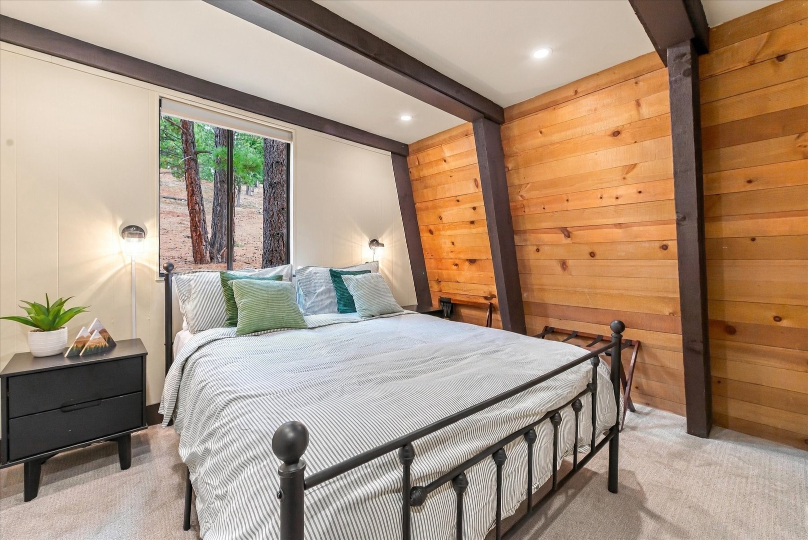 Your comfortable queen bedroom with cozy bedding and a forest view.