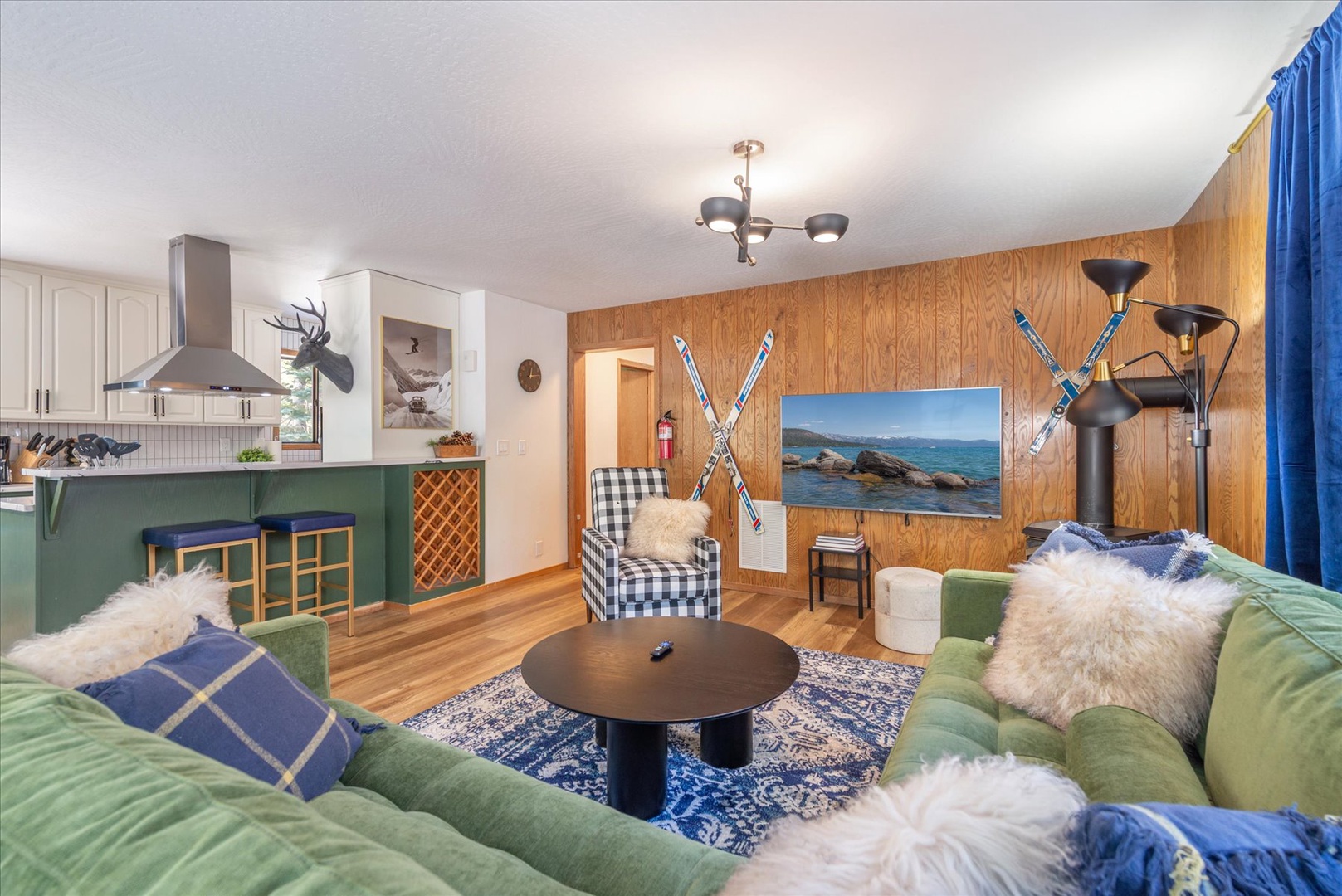 Cozy up in your mountain-themed living space with plush green sofas and warm wood paneling setting the vibe for après-ski lounging.