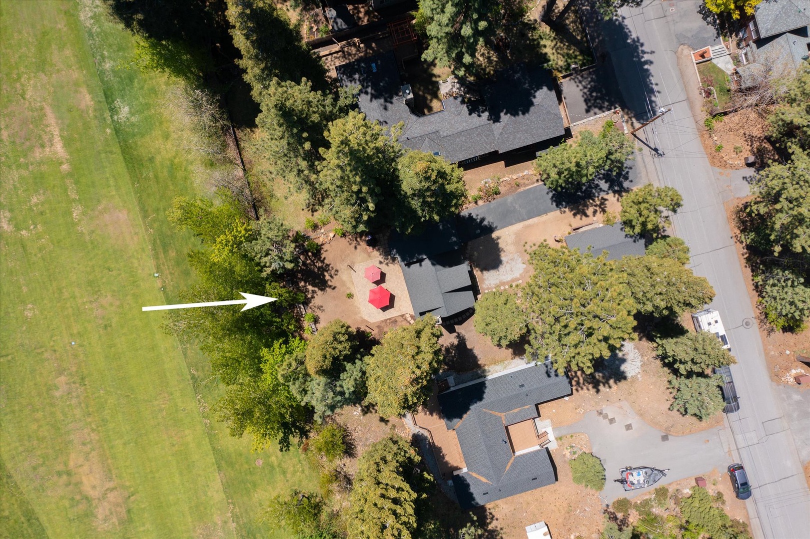 Aerial view of the property nestled among mature trees in a peaceful residential neighborhood with the golf course nearby.