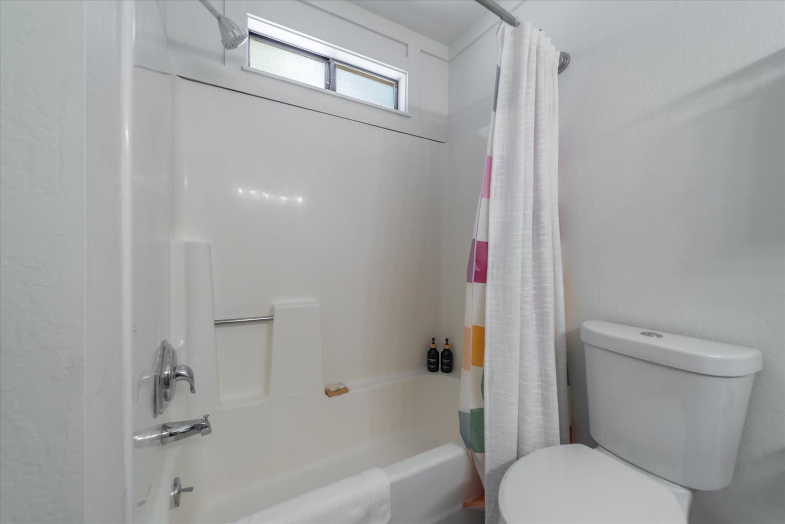 Spotlessly clean, this bathroom features a tub-shower combo, bright natural light from above, and colorful towels ready for your arrival.