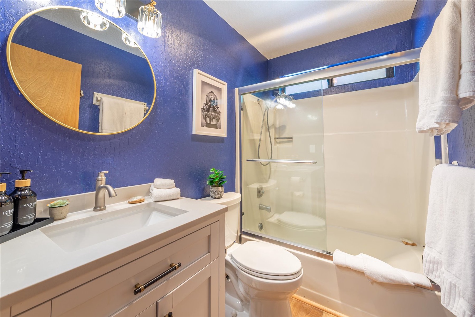 Step into your stylish bathroom with bold blue walls, modern fixtures, and fresh towels waiting for your arrival.