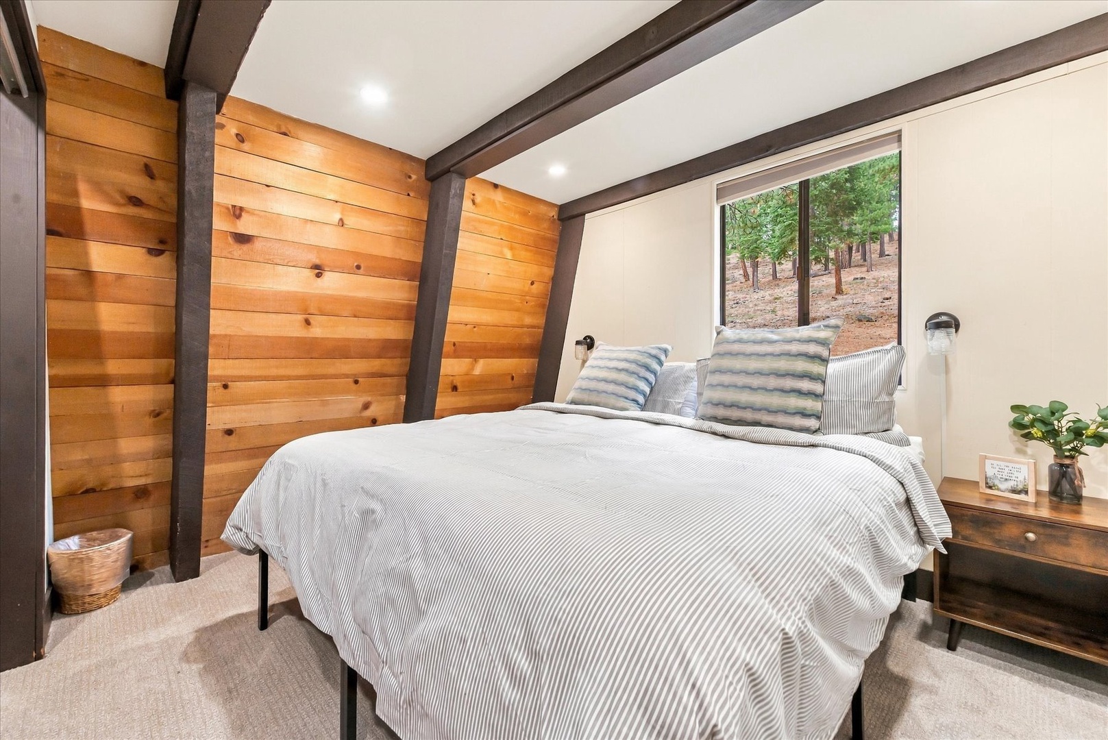 Drift off in your peaceful king bedroom, where warm wood walls and a window overlooking serene woods create a restful retreat surrounded by nature.