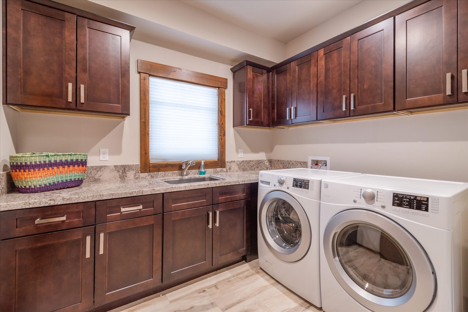 Your dedicated laundry room features rich wood cabinetry, granite countertops, and a convenient sink for easy care.