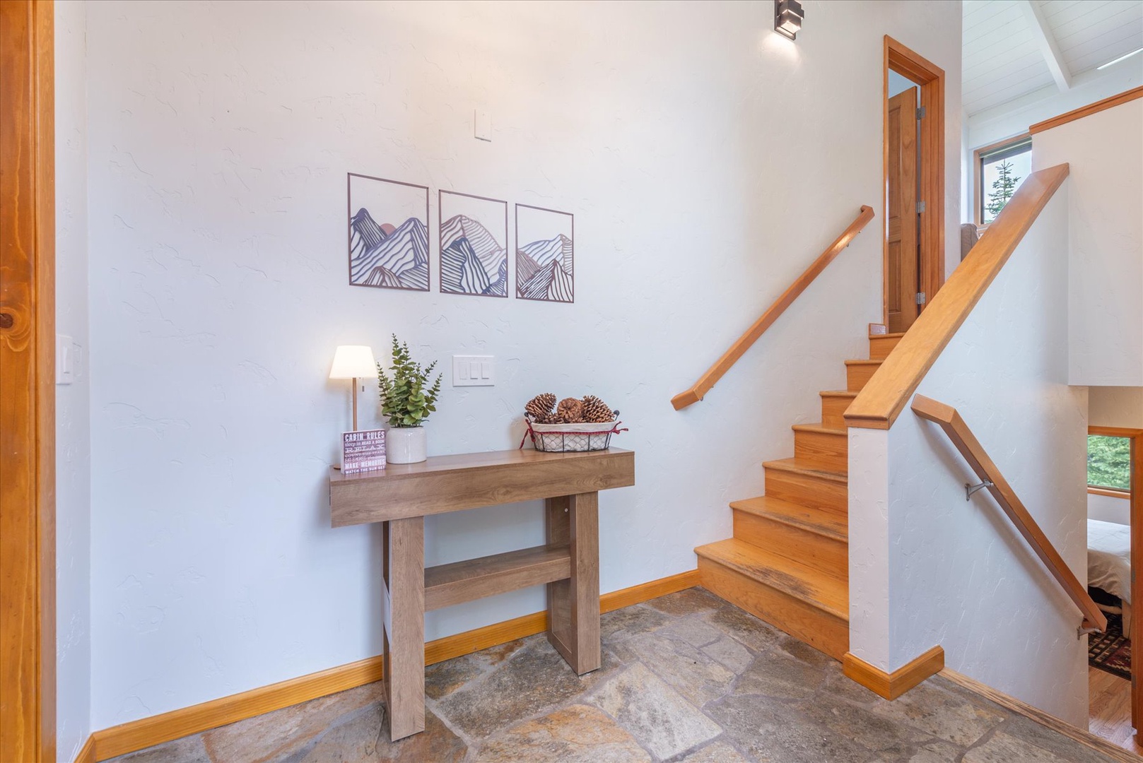 Step into your alpine retreat through a bright, welcoming entryway where warm wood accents and mountain-inspired art set the tone for your peaceful mountain escape.
