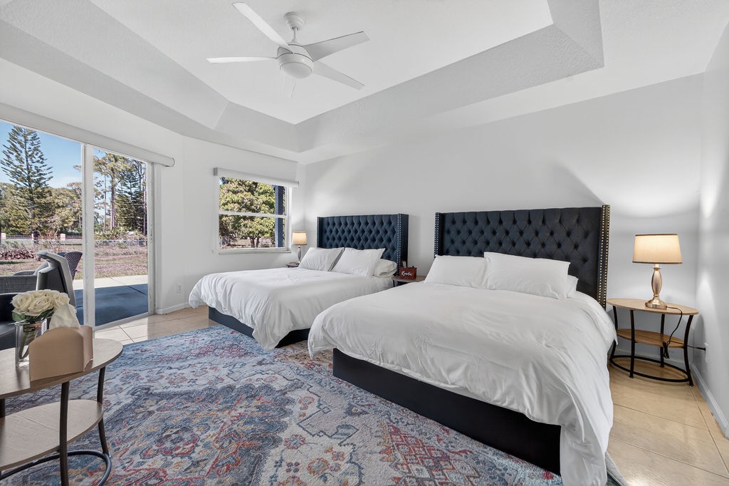 Drift off to sleep in this elegant twin bedroom with plush navy headboards, crisp linens, and natural light streaming through large windows.