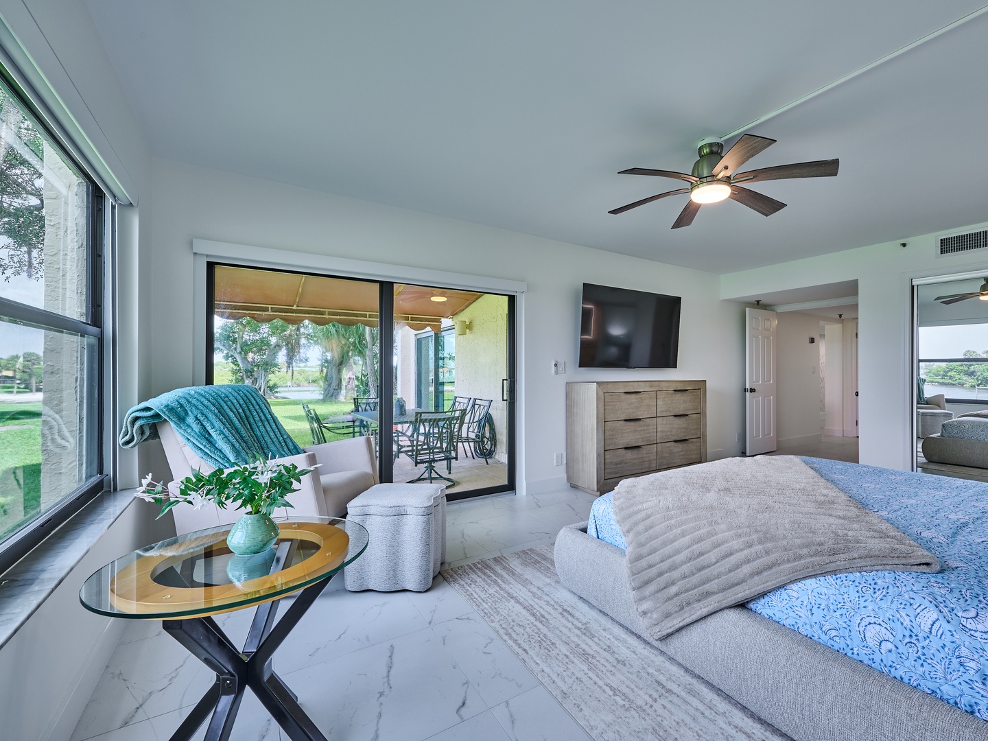 Relax in your serene bedroom where gentle breezes from the ceiling fan and natural light create the perfect retreat. Your private patio awaits just beyond the glass doors.