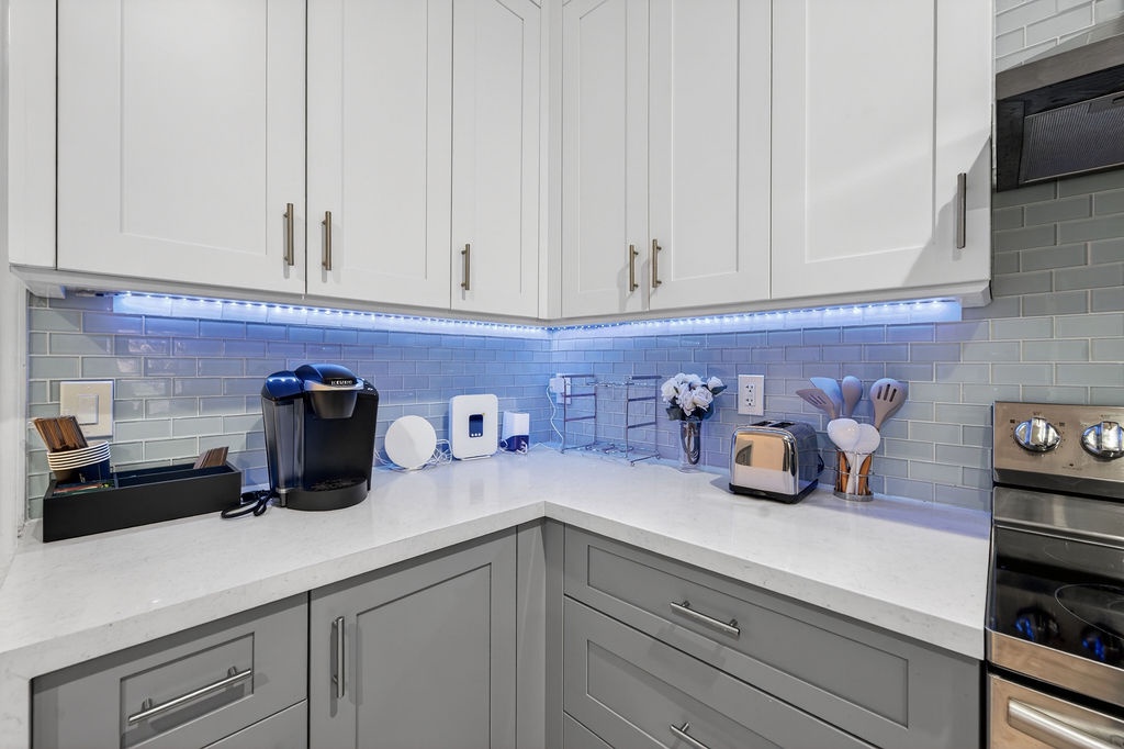 Your modern kitchen awaits with gleaming countertops, ambient LED lighting, and premium appliances including a coffee maker for perfect mornings.