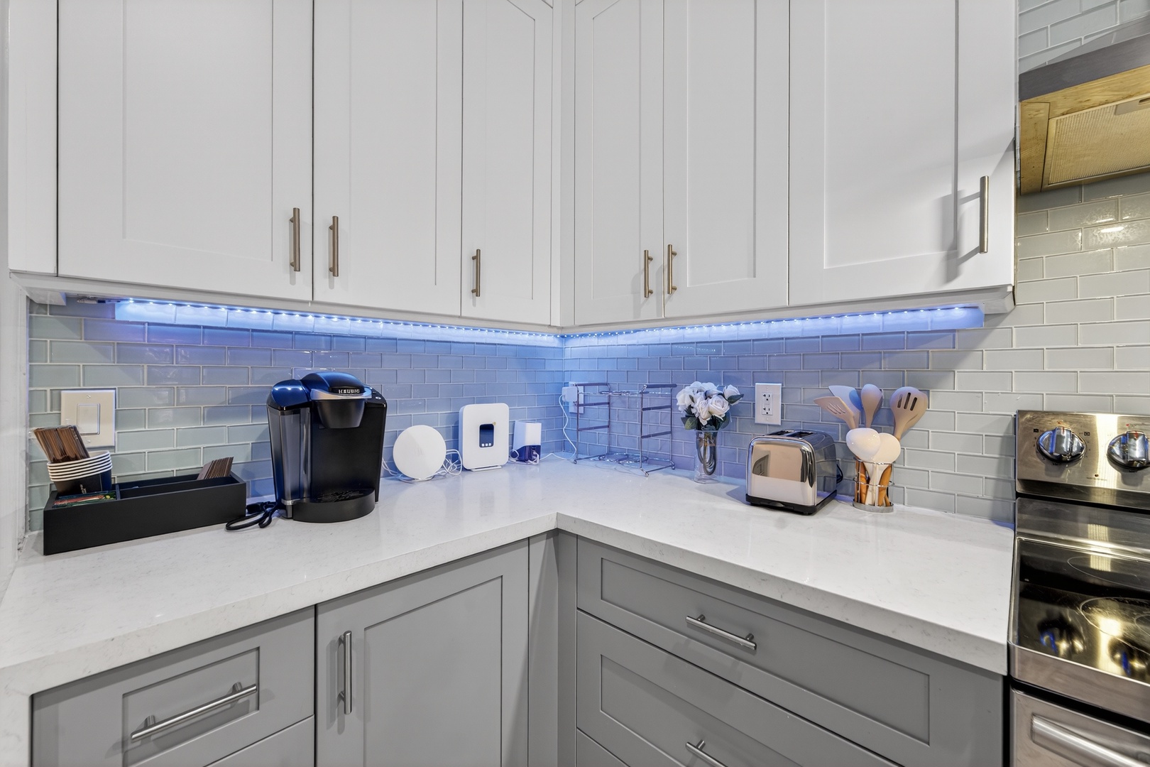 Your modern kitchen corner features sleek white cabinets with LED lighting, creating the perfect ambiance for morning coffee or evening meal prep.