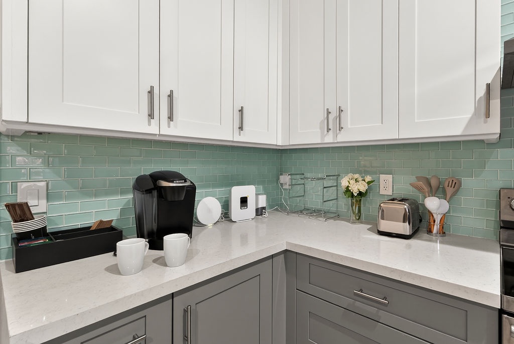 Start your mornings in this stylish corner kitchen with coffee maker, toaster, and fresh flowers creating the perfect breakfast setting.