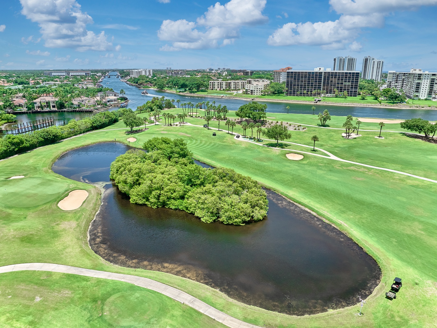 Aerial view of a championship golf course with lush fairways, water features, and palm-lined greens set along scenic waterways in a resort-style community.