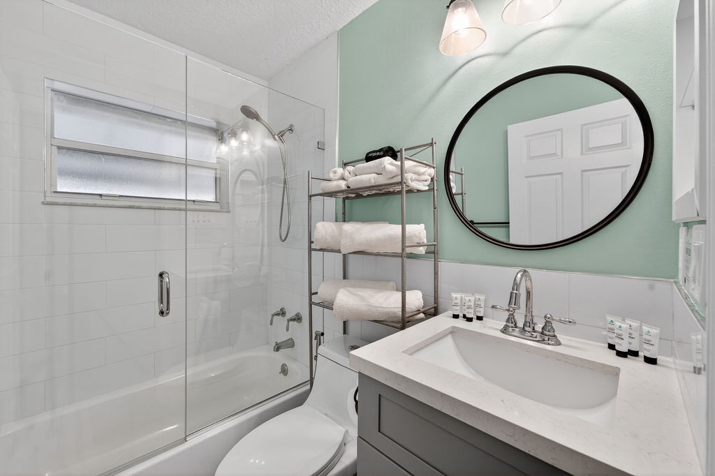 Refresh in your bright, modern bathroom featuring a glass shower, elegant vanity, and thoughtful touches like fluffy towels and amenities.