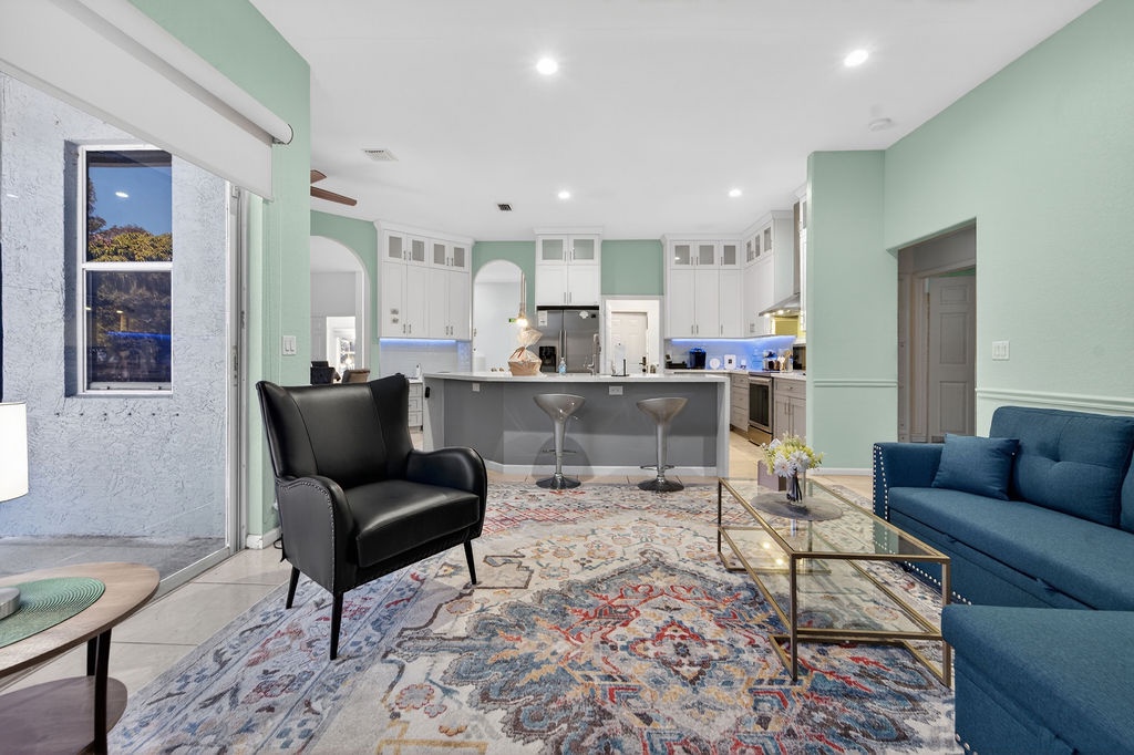 Relax in your spacious open-concept living space where mint-green walls complement rich navy seating and a sleek modern kitchen awaits your culinary adventures.