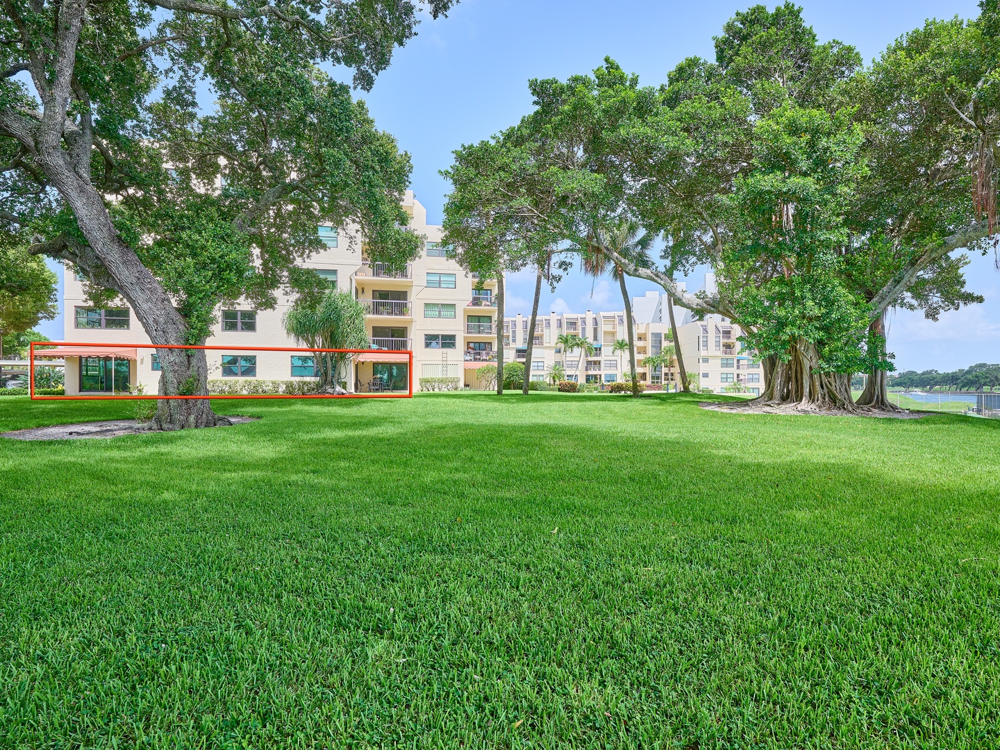A waterfront property surrounded by mature oak trees and expansive green lawns, offering a serene natural setting within a residential community.