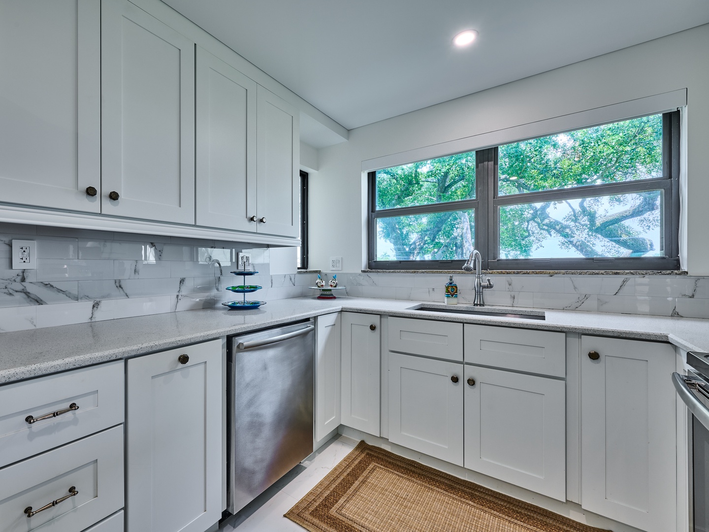 Your kitchen is sleek, modern, and fully equipped with everything you need to whip up a meal, including plenty of counter space and natural light from the lush garden view.