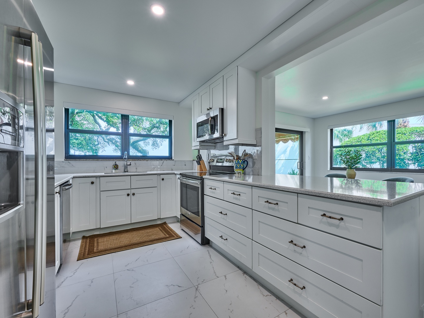 Step into this bright, modern kitchen with gleaming countertops, stainless steel appliances, and natural light streaming through the windows. You'll love preparing meals in this well-equipped space.