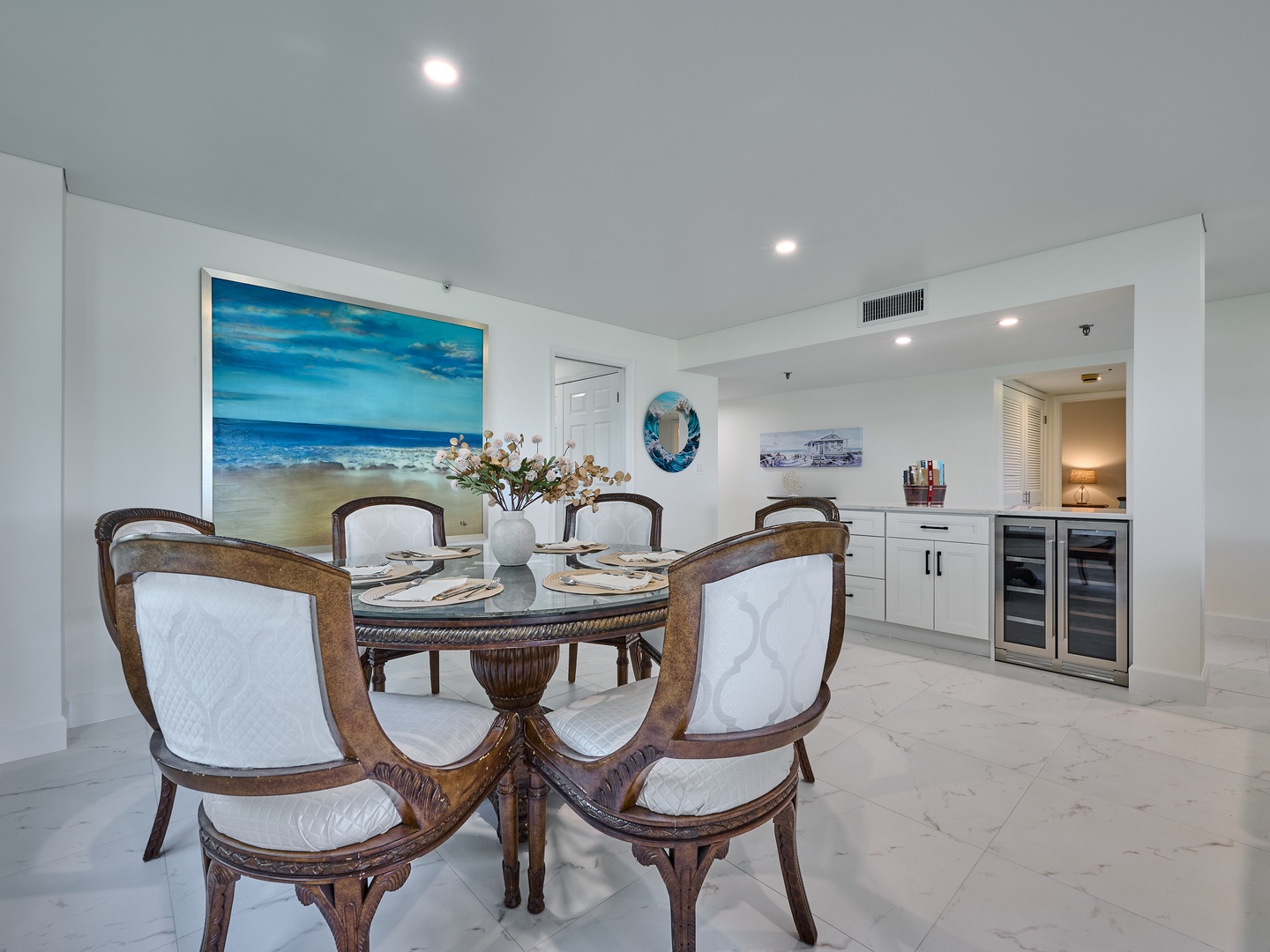 Gather around your beautifully set dining table, where coastal artwork and thoughtful touches create a welcoming space for meals and conversation. The open layout flows seamlessly to your kitchenette for effortless entertaining.