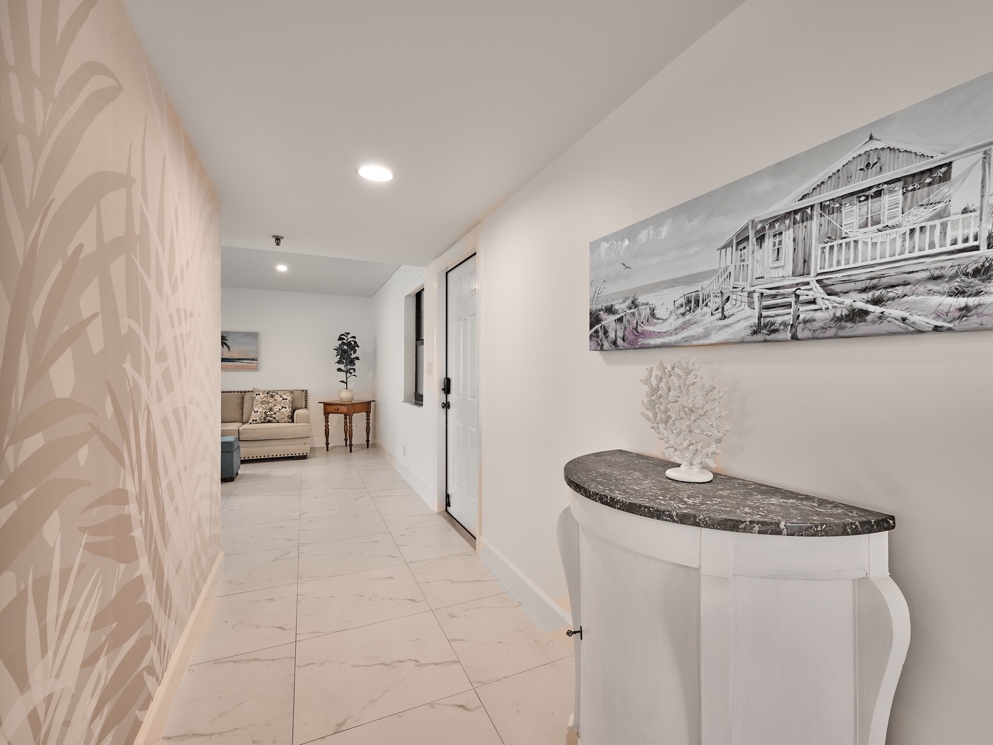 Step into a bright, welcoming hallway where your getaway begins. Subtle coastal accents and a serene sitting area await just beyond, inviting you to settle in and unwind.
