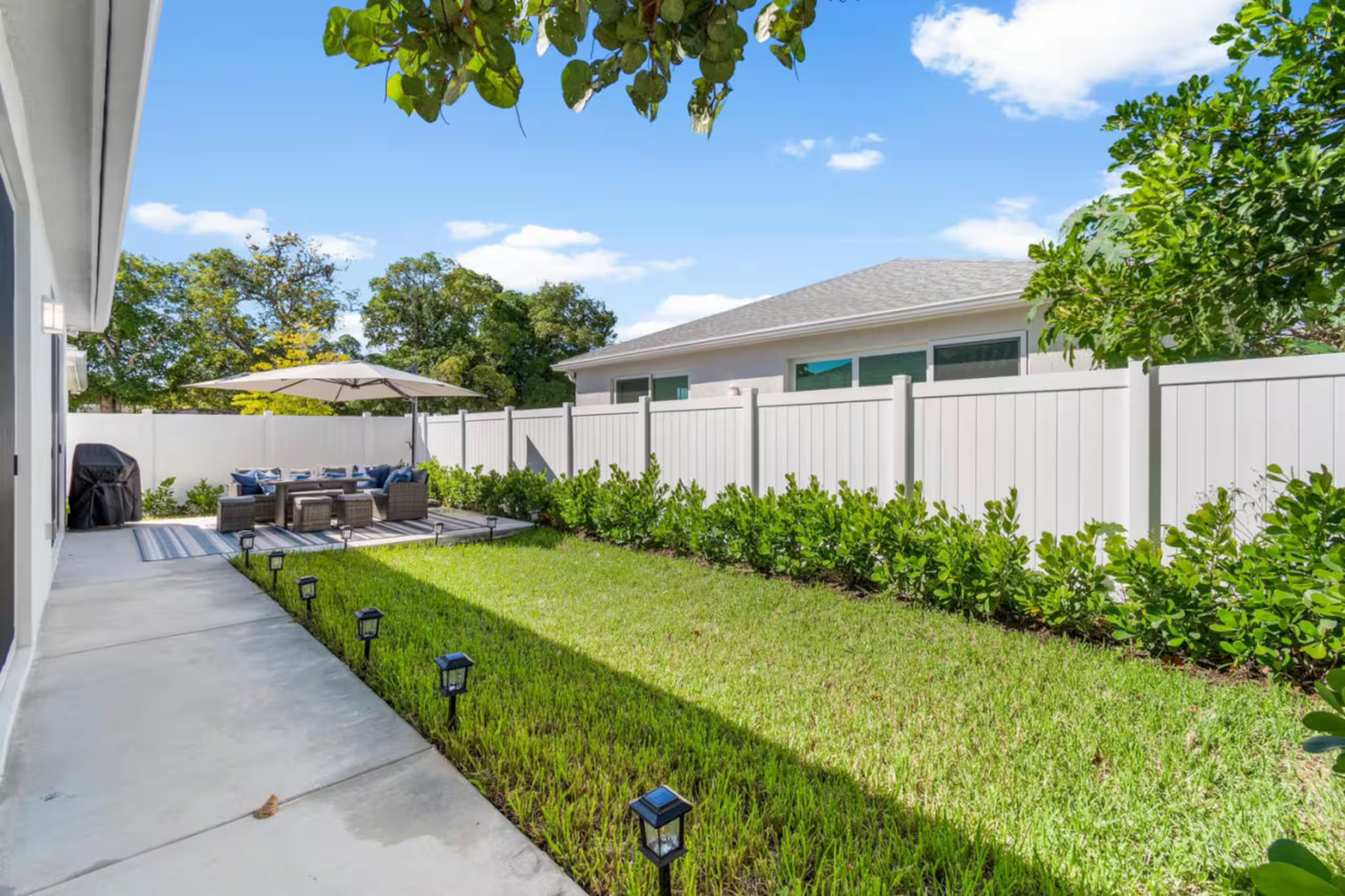 A spacious private backyard with lush green lawn, outdoor seating, and shaded patio—perfect for grilling, games, or simply unwinding under the Florida sunshine.