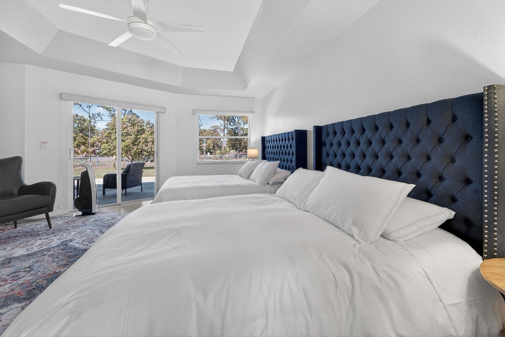 Sink into crisp white linens and luxurious tufted headboards in your elegant bedroom, where natural light and balcony access create the perfect retreat.